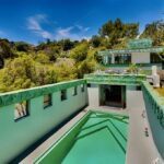 The green colored tile pool at the Samuel-Novarro House. Blue sky and green foliage. On Zero Hour Group site.